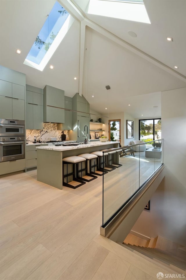 interior space with beamed ceiling, a kitchen bar, backsplash, a skylight, and modern cabinets