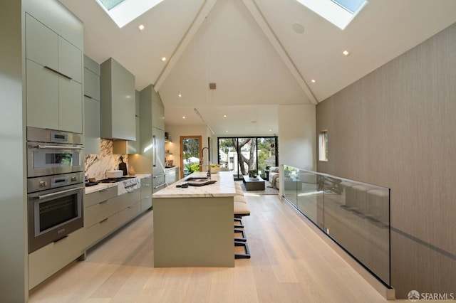 kitchen featuring a skylight, high vaulted ceiling, modern cabinets, and a sink