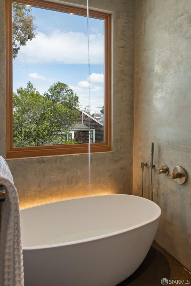 bathroom with a freestanding tub and a healthy amount of sunlight