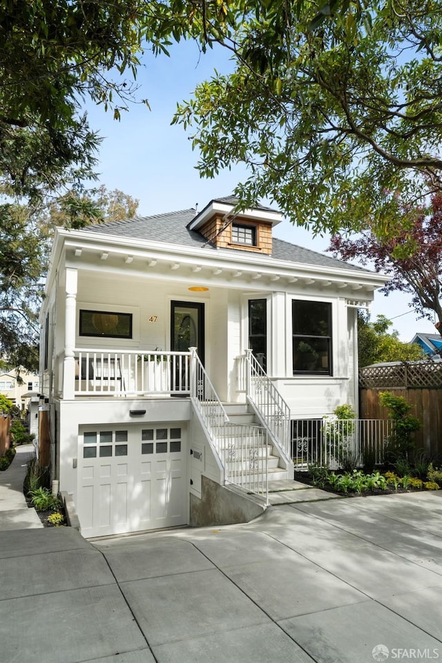 view of front of property with concrete driveway, an attached garage, fence, and a shingled roof