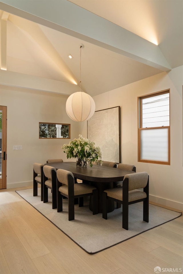 dining space featuring a healthy amount of sunlight, baseboards, vaulted ceiling, and light wood-style flooring