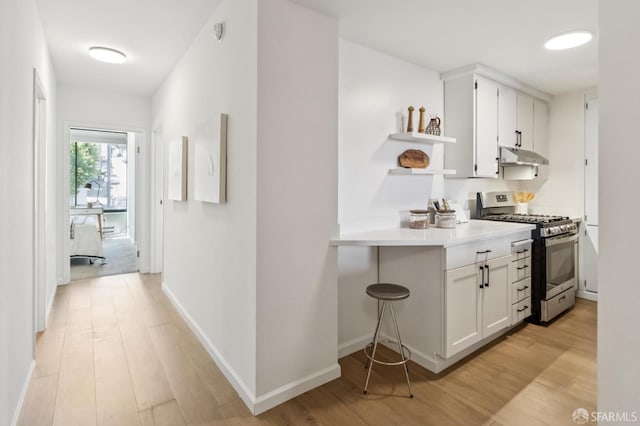 1520 Taylor St Unit 103, San Francisco, CA 94133 - kitchen featuring stainless steel gas stove, under cabinet range hood, open shelves, light wood finished floors, and white cabinetry