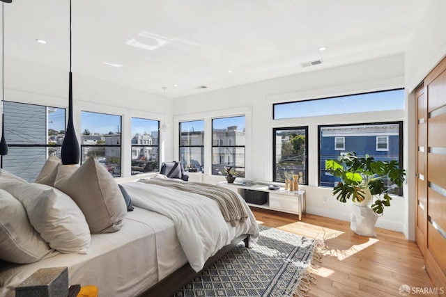 bedroom with visible vents, a view of city, recessed lighting, light wood-style floors, and baseboards