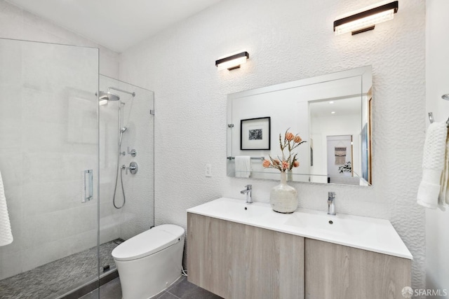 bathroom featuring double vanity, toilet, a stall shower, and a sink