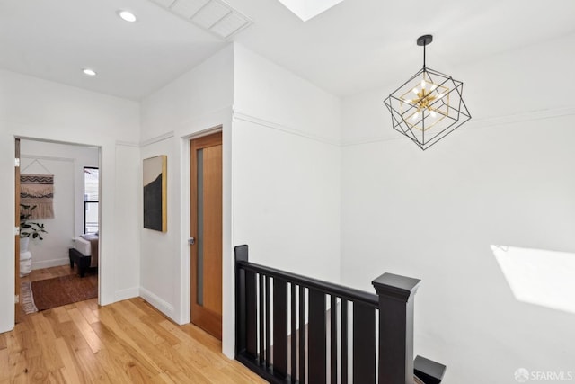 hallway with visible vents, recessed lighting, an inviting chandelier, a skylight, and light wood finished floors