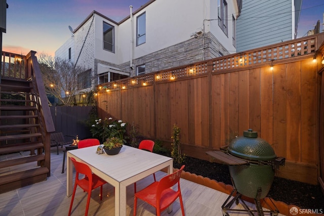 view of patio / terrace featuring outdoor dining space, stairway, and a fenced backyard