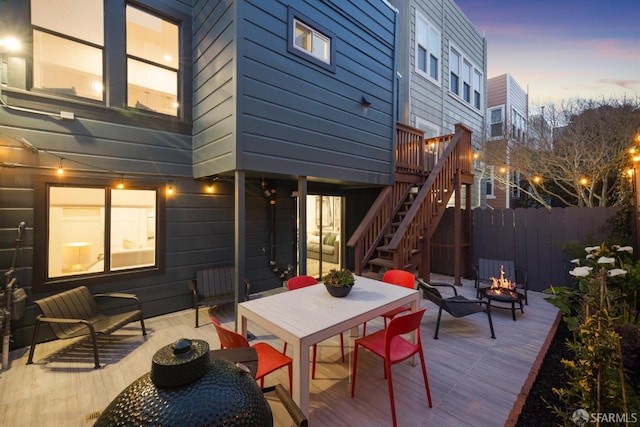 wooden deck featuring a fire pit, outdoor dining area, stairs, and fence