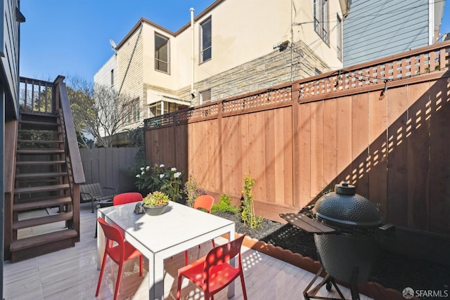 view of patio featuring stairway, outdoor dining space, a wooden deck, and a fenced backyard