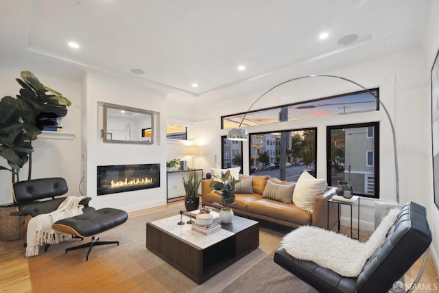 living area featuring recessed lighting, baseboards, wood finished floors, and a glass covered fireplace