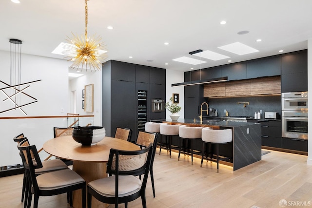 dining room with a notable chandelier, sink, and light wood-type flooring