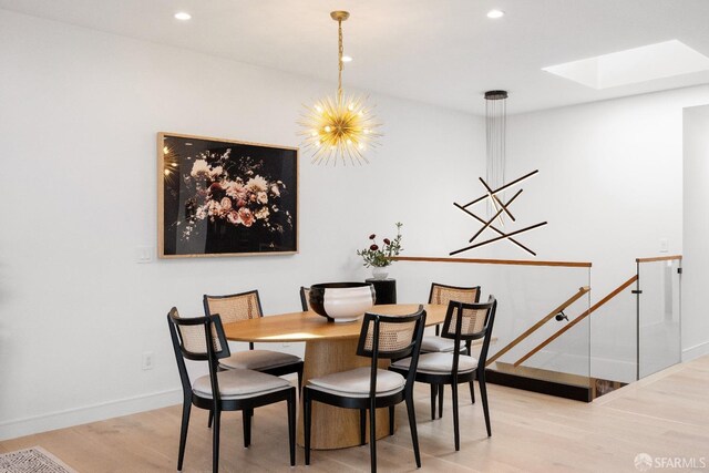 dining area with a skylight, light hardwood / wood-style flooring, and a notable chandelier