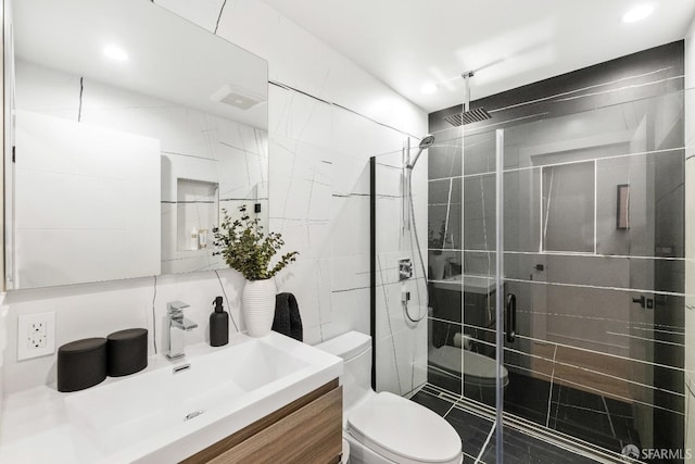 bathroom featuring toilet, a shower with shower door, tile walls, vanity, and decorative backsplash