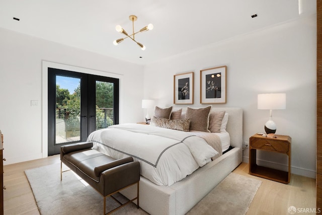 bedroom featuring a chandelier, access to outside, light wood-type flooring, and french doors