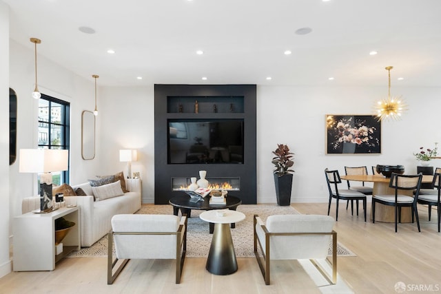 living room featuring an inviting chandelier, a fireplace, and light hardwood / wood-style floors