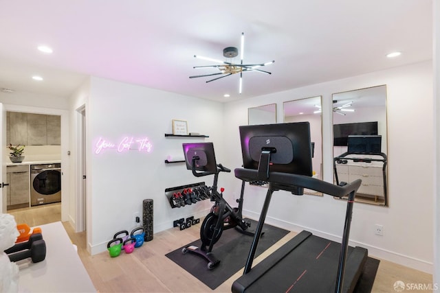 workout area featuring wood-type flooring, washer / clothes dryer, and a chandelier