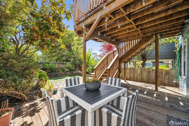deck featuring a fenced backyard, a patio, outdoor dining area, and stairway