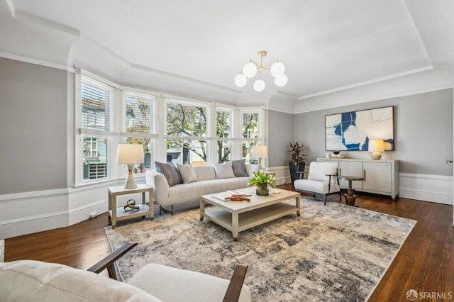 living area with a tray ceiling, a chandelier, plenty of natural light, and wood finished floors