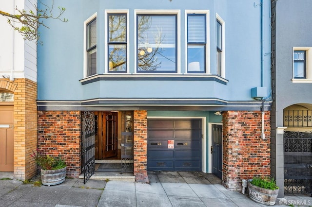 view of front of house with an attached garage, stucco siding, and brick siding