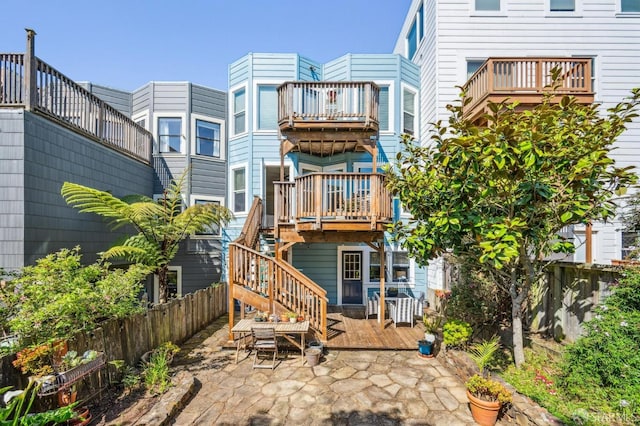 back of property with stairway, a patio, fence, and a deck