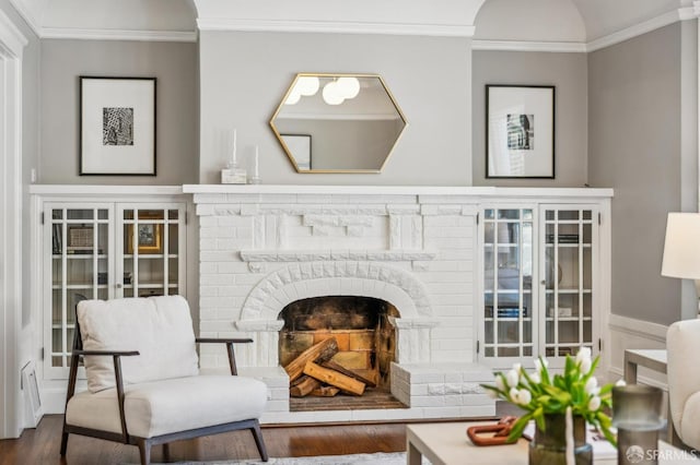 sitting room with ornamental molding, a fireplace, and wood finished floors