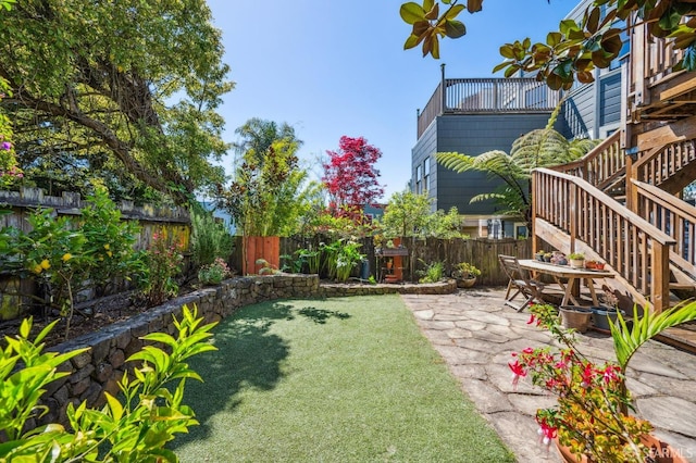 view of yard featuring a fenced backyard, a patio, and stairway