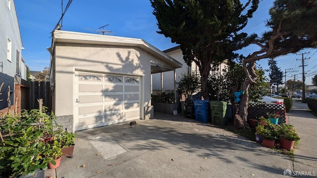 exterior space featuring an outbuilding, driveway, fence, a garage, and stucco siding