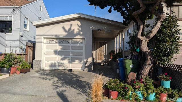 view of home's exterior featuring an attached garage, driveway, fence, and stucco siding