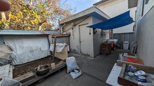 view of property exterior featuring fence, a storage unit, an outdoor structure, and stucco siding