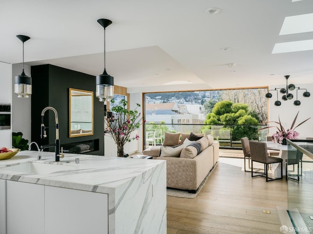 living room featuring sink, light hardwood / wood-style flooring, a skylight, and a wealth of natural light