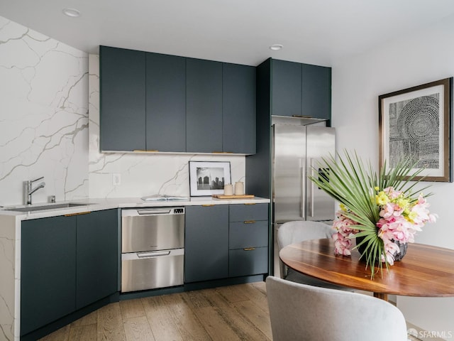 kitchen featuring backsplash, appliances with stainless steel finishes, hardwood / wood-style flooring, and blue cabinetry