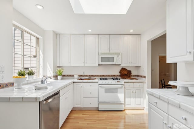 kitchen with tile countertops, white cabinetry, light wood finished floors, and white appliances