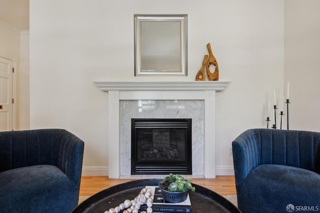 sitting room featuring a high end fireplace, baseboards, and wood finished floors