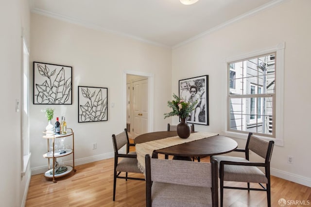dining room featuring crown molding, baseboards, and light wood-style floors