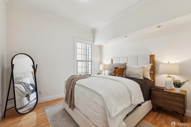 bedroom featuring baseboards, ornamental molding, and light wood finished floors