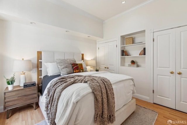 bedroom featuring crown molding, light wood-style floors, and two closets