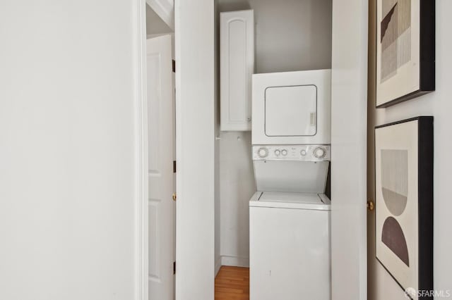 laundry area with laundry area, stacked washer / dryer, and wood finished floors