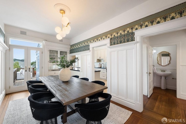 dining room with a chandelier, french doors, visible vents, and light wood-style flooring