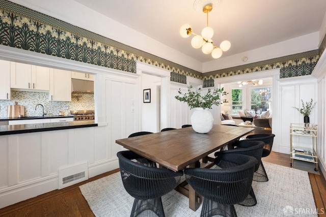 dining space featuring dark wood-style floors, visible vents, and an inviting chandelier