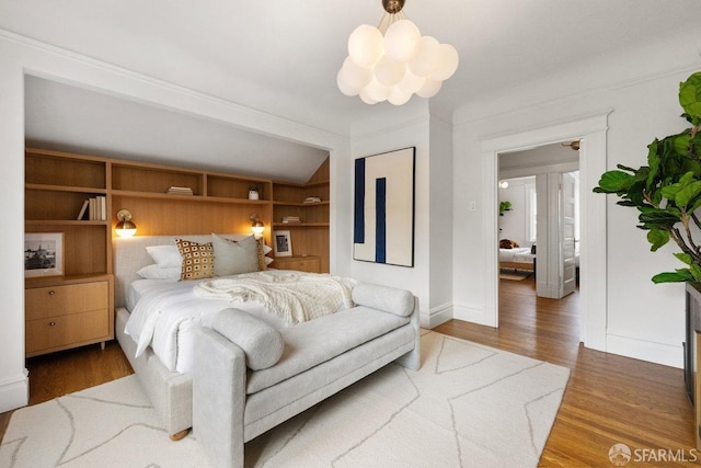 bedroom with a notable chandelier, baseboards, and wood finished floors