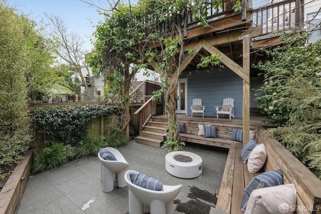 view of patio / terrace featuring an outdoor fire pit, fence, and a deck