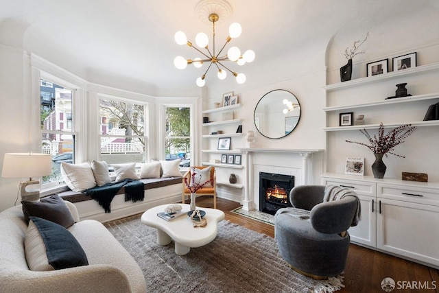 living room featuring dark wood-type flooring, a wealth of natural light, a notable chandelier, and a fireplace