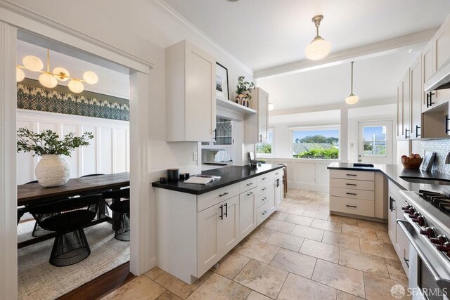 kitchen with decorative light fixtures, crown molding, dark countertops, a sink, and high end stove