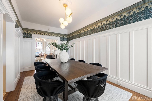 dining room with a chandelier, wood finished floors, and wallpapered walls