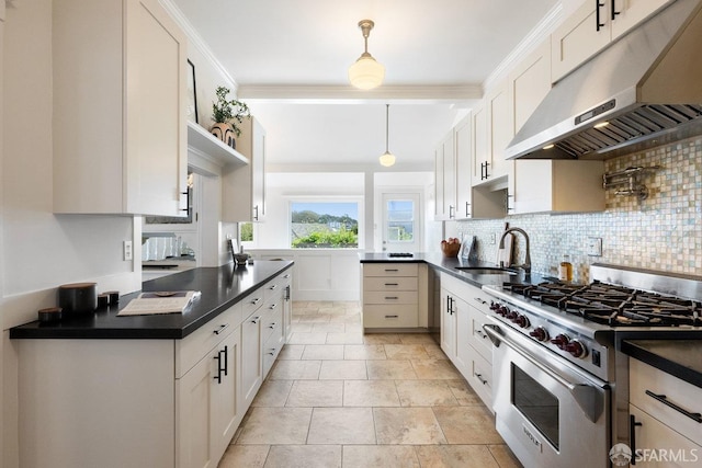 kitchen with high end stove, under cabinet range hood, dark countertops, and a sink