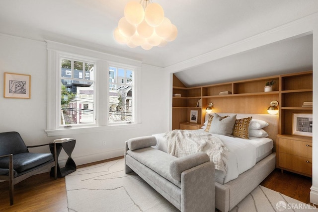 bedroom featuring vaulted ceiling, baseboards, wood finished floors, and an inviting chandelier