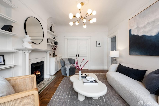 living room with dark wood-type flooring, a notable chandelier, a fireplace, and baseboards