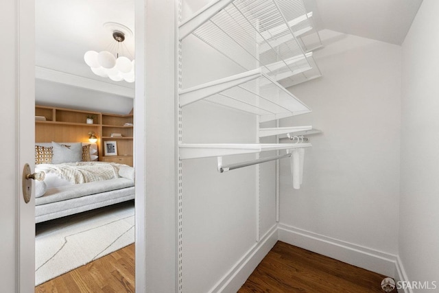 spacious closet with a notable chandelier and wood finished floors