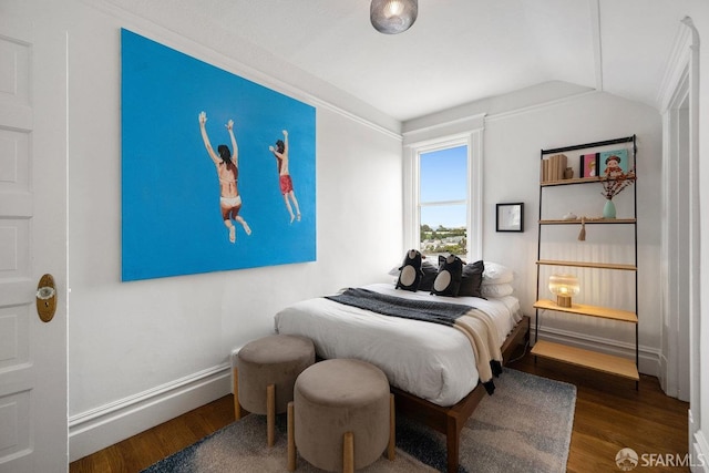 bedroom featuring lofted ceiling, baseboards, and wood finished floors