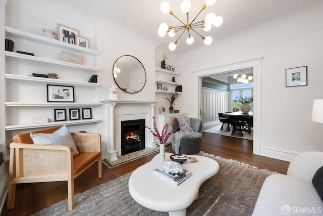 living area featuring an inviting chandelier, a brick fireplace, baseboards, and wood finished floors