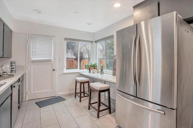 kitchen featuring gray cabinets, light tile patterned floors, and appliances with stainless steel finishes